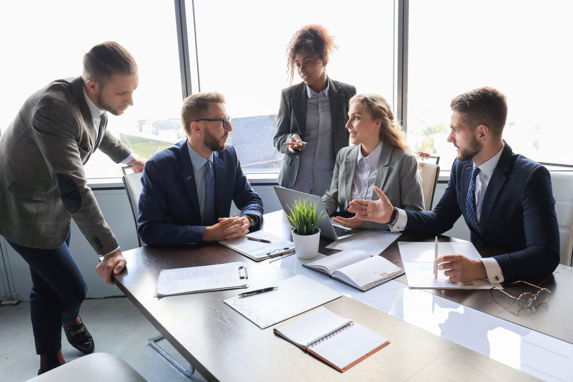 Group of young modern people in formalwear smiling and discussing something while working in the modern office.